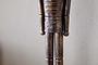 A close-up of the Imay Nutcracker - Antique Brass by nkuku shows its textured dark brown and gold finish, stylized cylindrical arms, and decorative waist carvings—perfect for festive or seasonal displays.