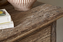 Close-up of the nkuku Ibo Reclaimed Wood 1 Drawer Console Table in Natural, its rustic surface displaying a striped ceramic vase and two stacked books, one with fruit illustrations on the cover.