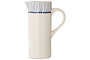 The Iba Jug - Indigo by nkuku is a tall, white ceramic pitcher featuring artisanal craftsmanship, a curved handle, narrow spout, and thin indigo lines near the rim for a modern touch.