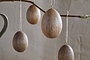 The Dima Mango Wood Hanging Egg Decoration - Natural (set of 4) by nkuku features smooth, brown mango wood eggs suspended from twine, adding a rustic, natural charm—ideal for subtle Easter décor.