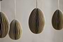 Four moss green, oval-shaped Piani Hanging Paper Decorations by nkuku hang from strings against a neutral background. The set of 4 recycled paper ornaments is spaced apart, with focus on the two in the center.