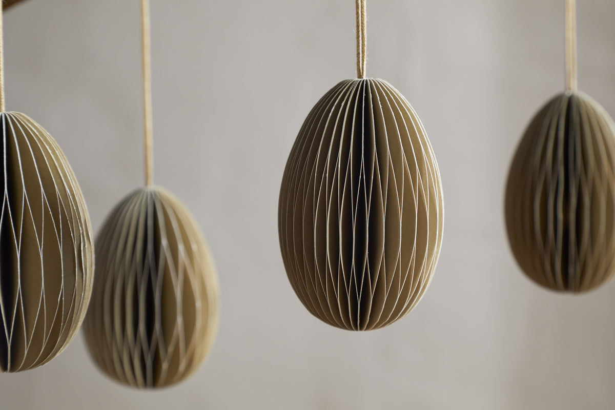 Four moss green, oval-shaped Piani Hanging Paper Decorations by nkuku hang from strings against a neutral background. The set of 4 recycled paper ornaments is spaced apart, with focus on the two in the center.