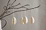 A ceramic vase holds a bare branch with buds, adorned with nkuku's Piani Hanging Paper Decoration - Cream (Set of 4), suspended by white strings. The recycled paper eggs stand out against a softly textured beige wall for a minimal, delicate look.
