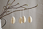 A ceramic vase holds a bare branch with buds, adorned with nkuku's Piani Hanging Paper Decoration - Cream (Set of 4), suspended by white strings. The recycled paper eggs stand out against a softly textured beige wall for a minimal, delicate look.