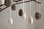 The nkuku Piani Mini Hanging Paper Decoration set features 12 natural and moss-colored honeycomb eggs, crafted from recycled paper and hung on white strings—perfect for adding unique texture to any space.