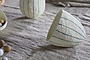 The nkuku Surya Recycled Cotton Paper Standing Opening Egg in teal and cream sits open on a textured beige Easter table, with more decorative eggs in the background for a soft, neutral display.