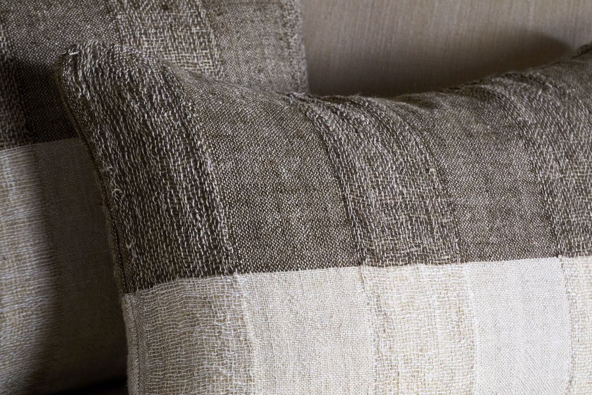 The Munir Linen Cushion Cover by nkuku features a slubby, woven texture in earthy brown and charcoal with rustic stripes—perfect for adding natural charm to your space.