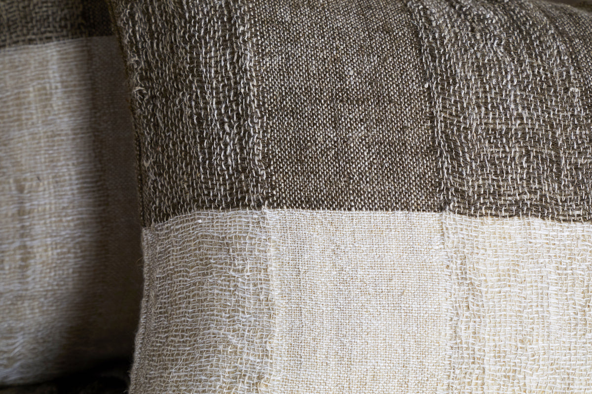 Close-up of the Munir Linen Cushion Cover by nkuku, showcasing wide charcoal and off-white stripes. Crafted from natural linen with a slubby texture, it offers a tactile, rustic look perfect for any cushion or pillow.