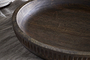 Close-up of the Eisha Bowl - Brown by nkuku, a large, hand-carved wooden serving bowl. Its rich wood grain and smooth finish stand out on light fabric, highlighting its rustic, handcrafted appeal.