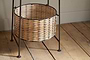 The Montali Iron & Rattan Three-Tiered Storage Stand by nkuku features handwoven natural rattan baskets with light and dark brown stripes on a black metal frame—perfect for stylish, practical kitchen or pantry organization.