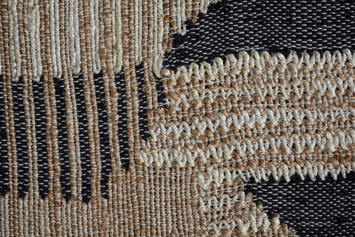 Close-up of the Birala Large Textured Wall Art by nkuku, handwoven with tan, cream, and dark blue threads in vertical stripes and angled shapes, showcasing intricate Indian-inspired design on a textured background.