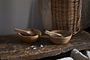 The nkuku Daruka Salt & Pepper Dipping Bowls with Spoons – Natural sit on a rustic surface. Coarse salt crystals and warm table accessories like a wicker basket and textured boards complete this inviting, natural set.