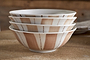 Four nkuku Patthar Cereal Bowls in Cream & Clay are stacked on wood. Each hand-painted bowl features vertical beige stripes and dotted lines, with the warm, blurred wooden background highlighting the artisan dinnerware’s charm.