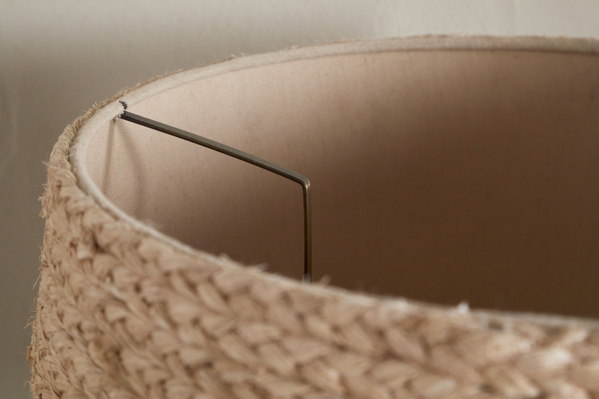 Close-up of the top edge of the nkuku Pisang Natural Lampshade, featuring an organic woven texture. The light beige fabric lining and metal frame inside are visible against an off-white wall.