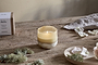 Candle on a wooden surface with natural elements and a box in the background