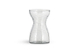 The Enir Hyacinth Vase - Clear by nkuku features clear hammered glass with a textured, dimpled surface and a narrow neck that curves to wide openings. The empty vase is shown against a plain white background.