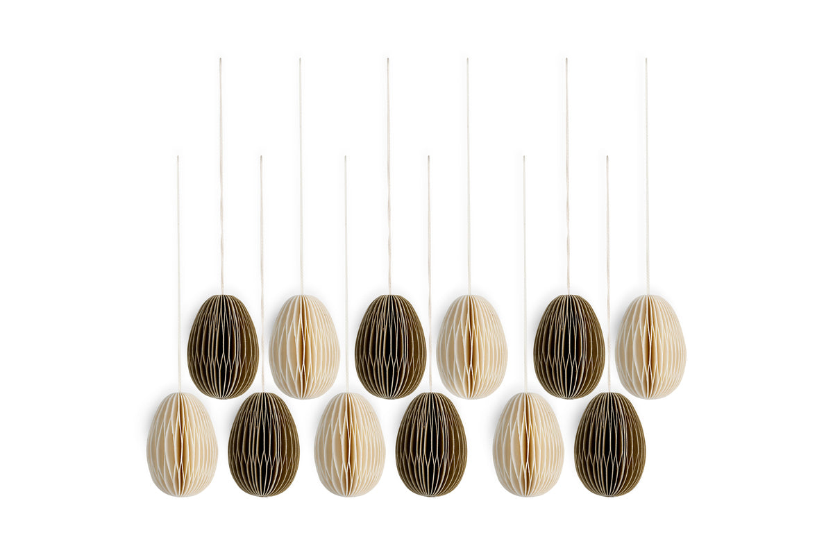 The nkuku Piani Mini Hanging Paper Decoration - Natural & Moss - Set of 12 features twelve oval paper eggs with vertical white and dark brown stripes, arranged in three rows of four for a minimalist, geometric display.