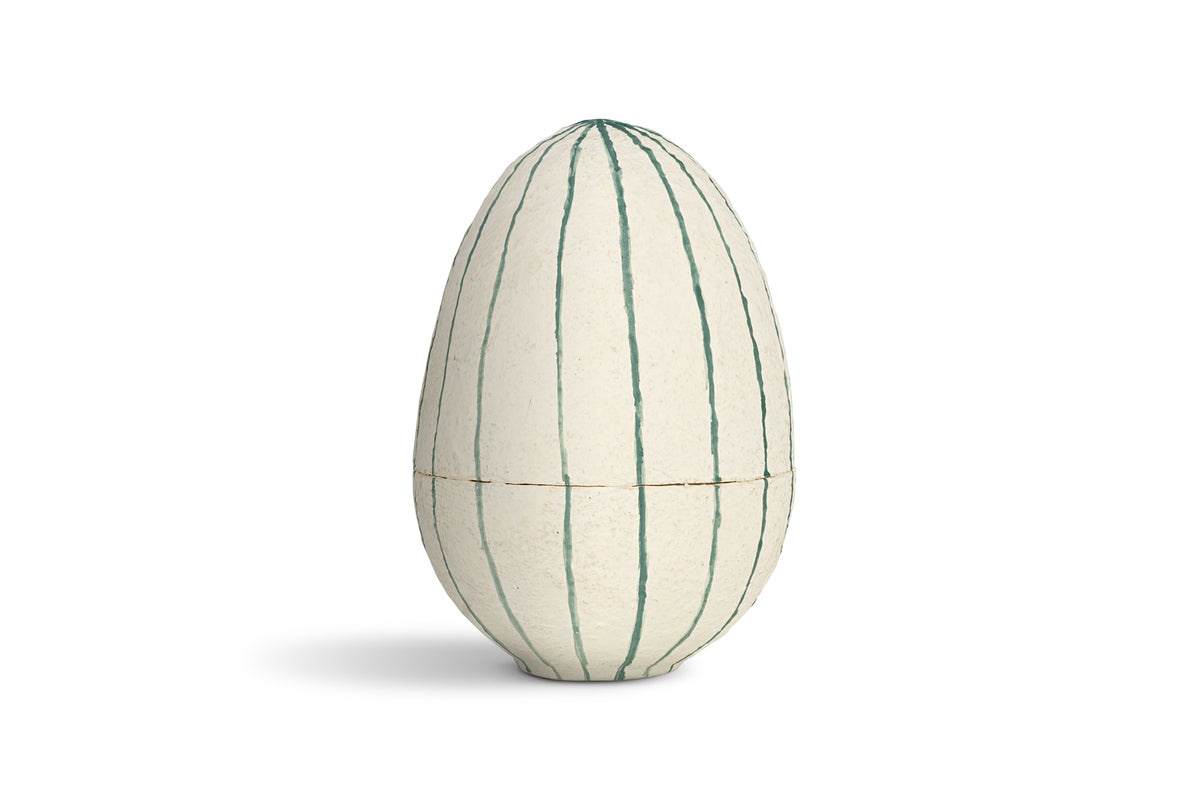 The nkuku Surya Recycled Cotton Paper Standing Opening Egg in teal and cream features a textured surface with vertical green lines. Made from recycled cotton paper, it brings charm to any Easter table setting.