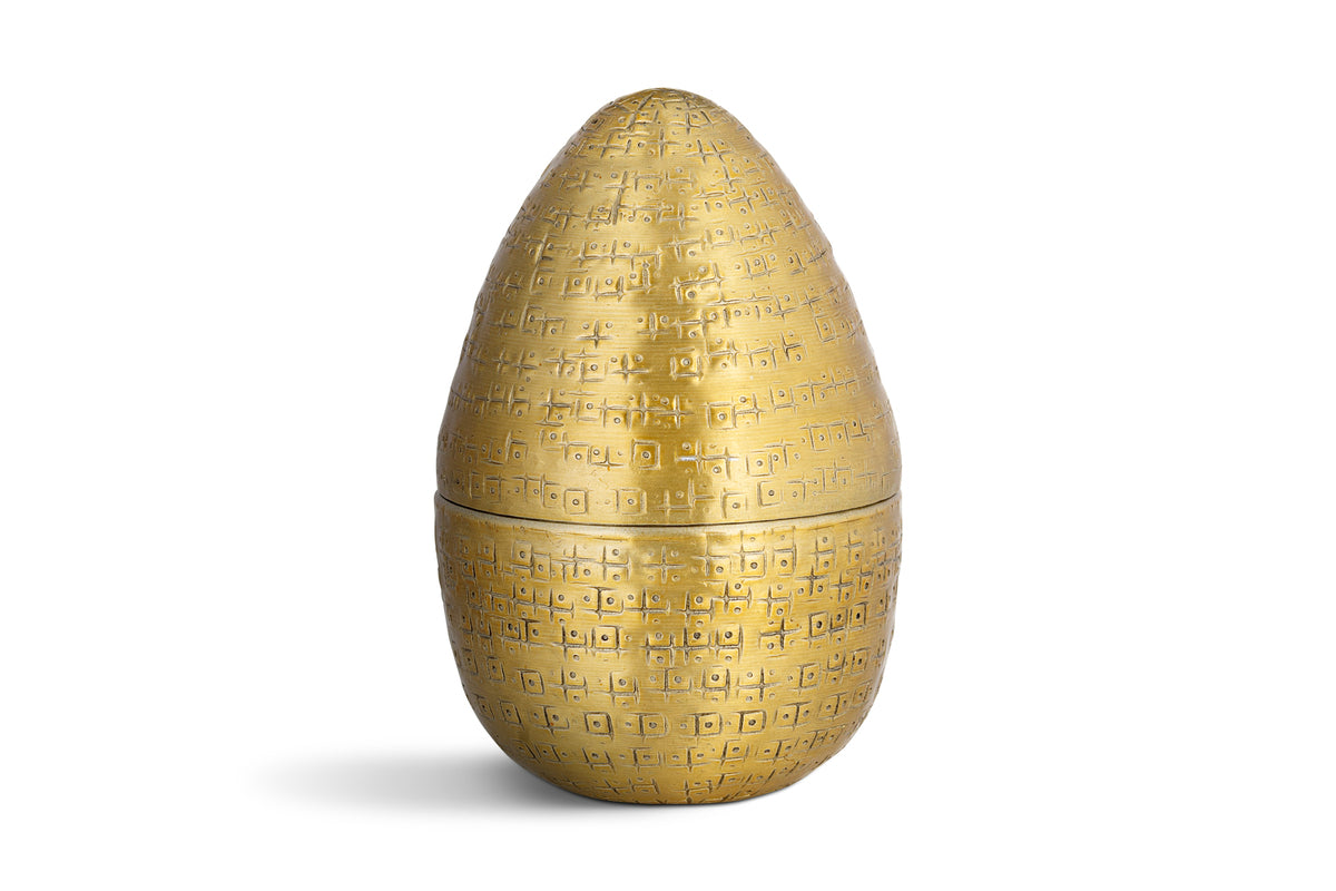 The Mutti Hammered Opening Egg by nkuku is an antique brass, egg-shaped container with a textured surface and a horizontal seam. This elegant Easter keepsake opens in two halves and is beautifully displayed against a plain white background.