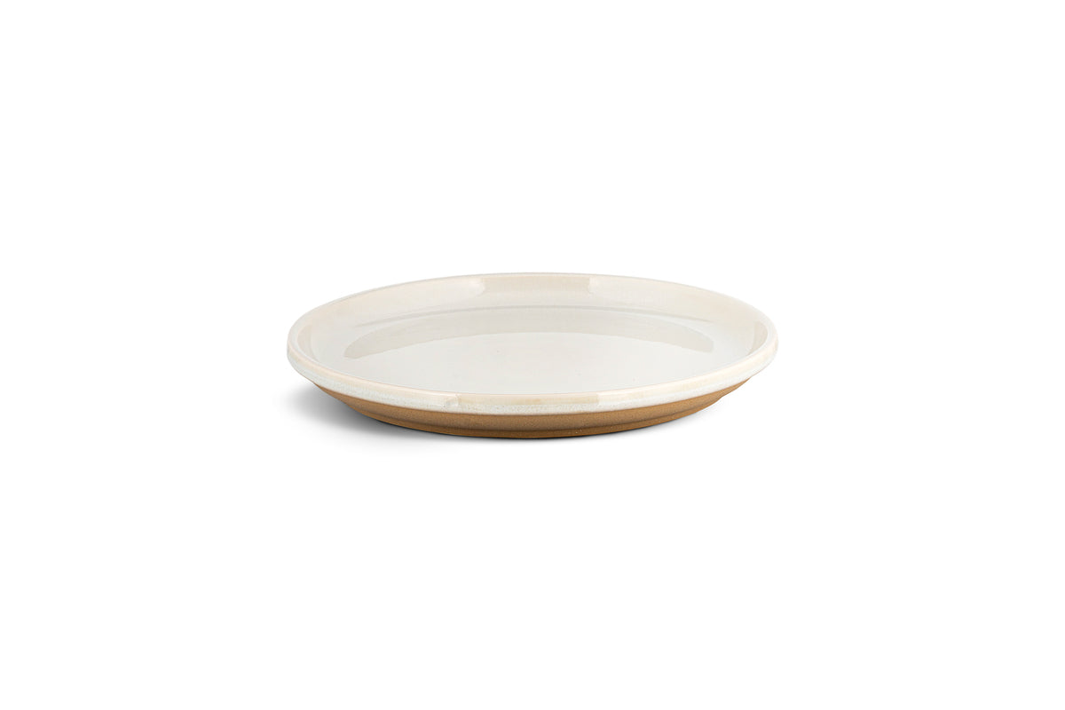 The nkuku Edo Dinnerware Set - Terracotta (Set of 12) features shallow, round ceramic plates with glossy white interiors and rims, contrasted by matte unglazed brown bases for a modern, earthy look, shown against a plain white background.