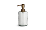 The nkuku Ilcoso Recycled Hammered Glass Soap Dispenser in clear features a cylindrical shape, antique brass pump, and elegant hammered design—perfect for adding style to any bathroom or kitchen. Stands empty against a plain white background.