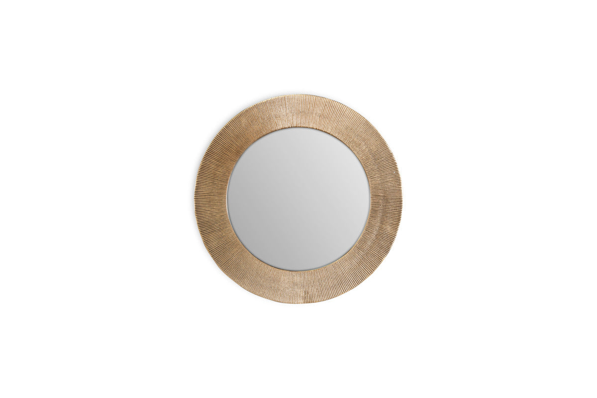 The Putali Etched Mirror by nkuku features a wide, textured antique brass frame with fine radiating lines. Its round design and decorative details make it a striking centerpiece on any plain white wall.