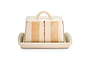 The Patthar Butter Dish - Cream & Clay by nkuku is hand-painted with vertical beige stripes and dotted accents. It features a curved handle, a fitted lid, and sits on a matching cream tray. Shown on a plain white background.