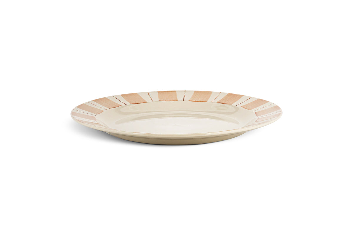 The nkuku Patthar Dinner Plate - Cream & Clay is a hand-painted, ceramic plate with a beige base and a rim of alternating peach and white segments edged with dashed lines. It has a shallow, round shape and a smooth, glossy finish.