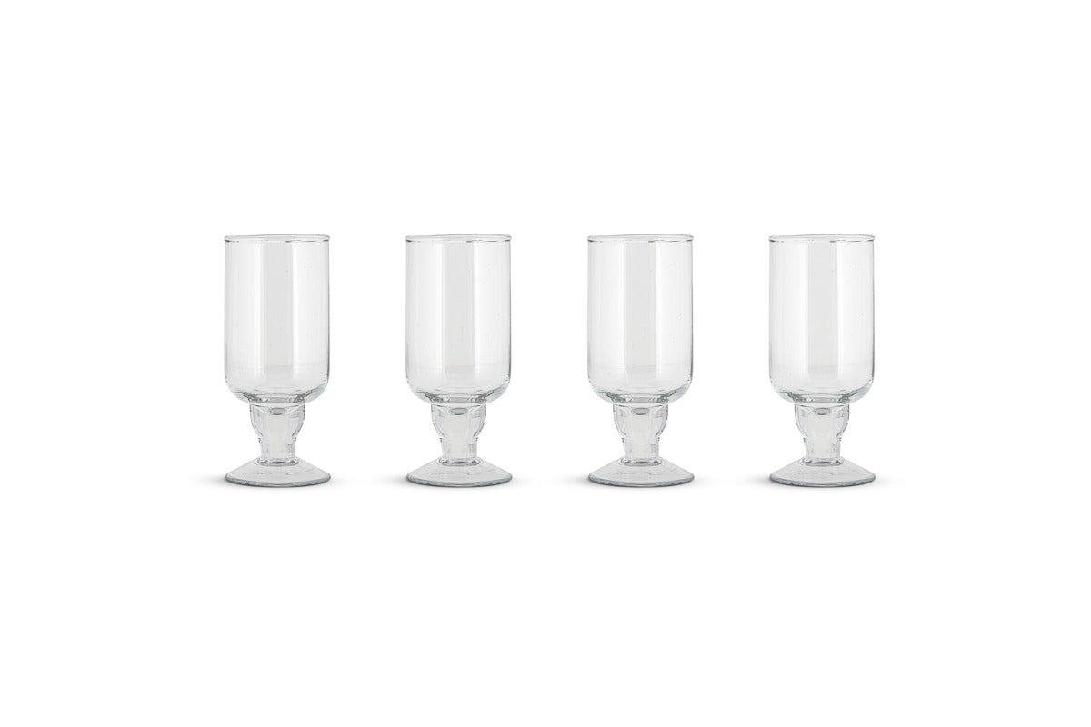 The Sooraj Large Glass - Clear (Set of 4) by nkuku features elegant, wide-based glass goblets with tall cylindrical bowls, perfectly arranged against a white background—ideal for stylishly serving summer drinks.