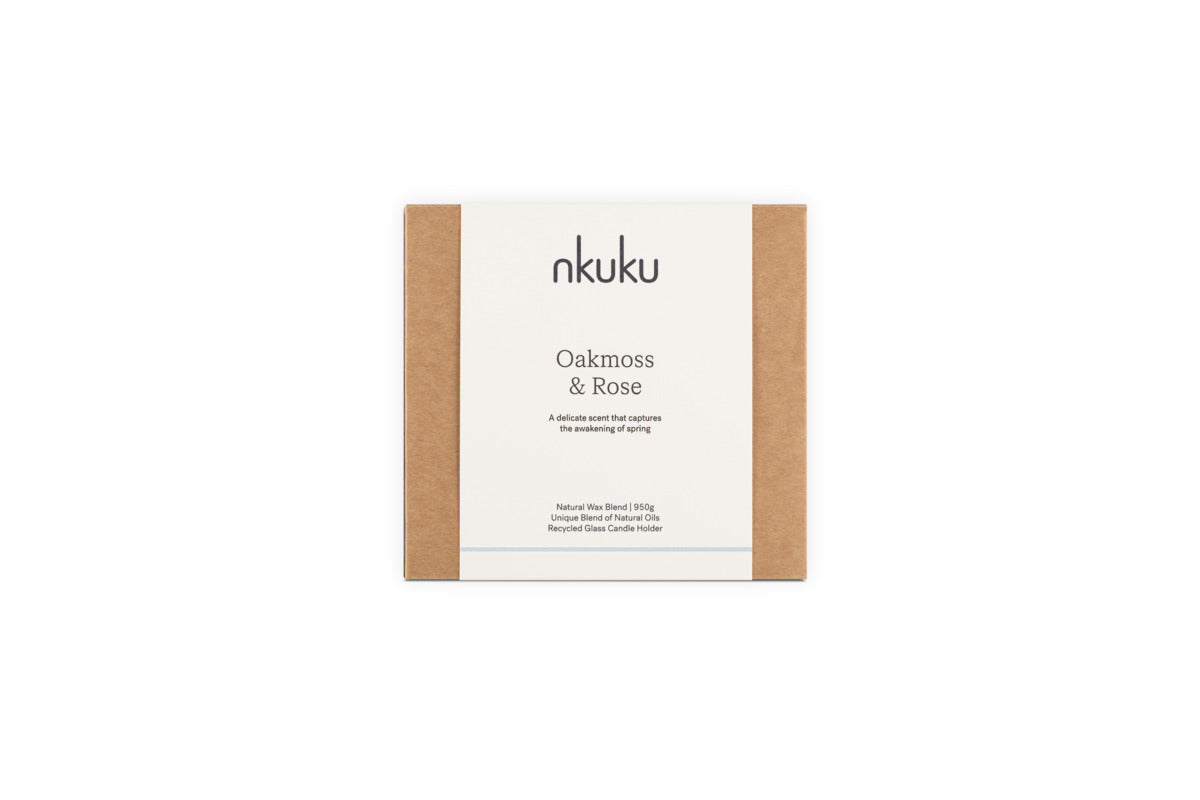 A rectangular nkuku Oakmoss & Rose 3 Wick Scented Candle - Yellow box with brown sides and a white label. This 170g candle features a spring scent, natural wax, unique essential oils, and comes in a recycled glass vessel.