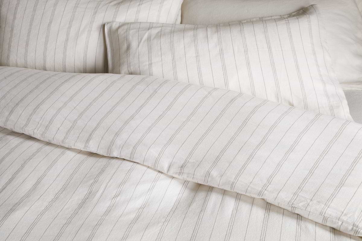 Close-up of a neatly made bed with the nkuku Anta Hemp & Cotton Duvet Cover in sage green, featuring breathable fabric for a clean and cozy look.