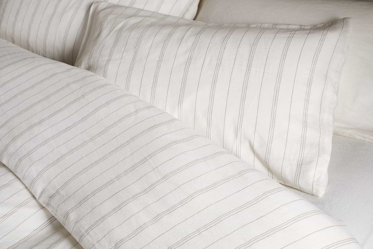 Close-up of a neatly made bed with the nkuku Anta Hemp & Cotton Duvet Cover in sage green, paired with matching pillow and sheet for a fresh, airy look. Bedding features breathable hemp-cotton blend for comfort and style.