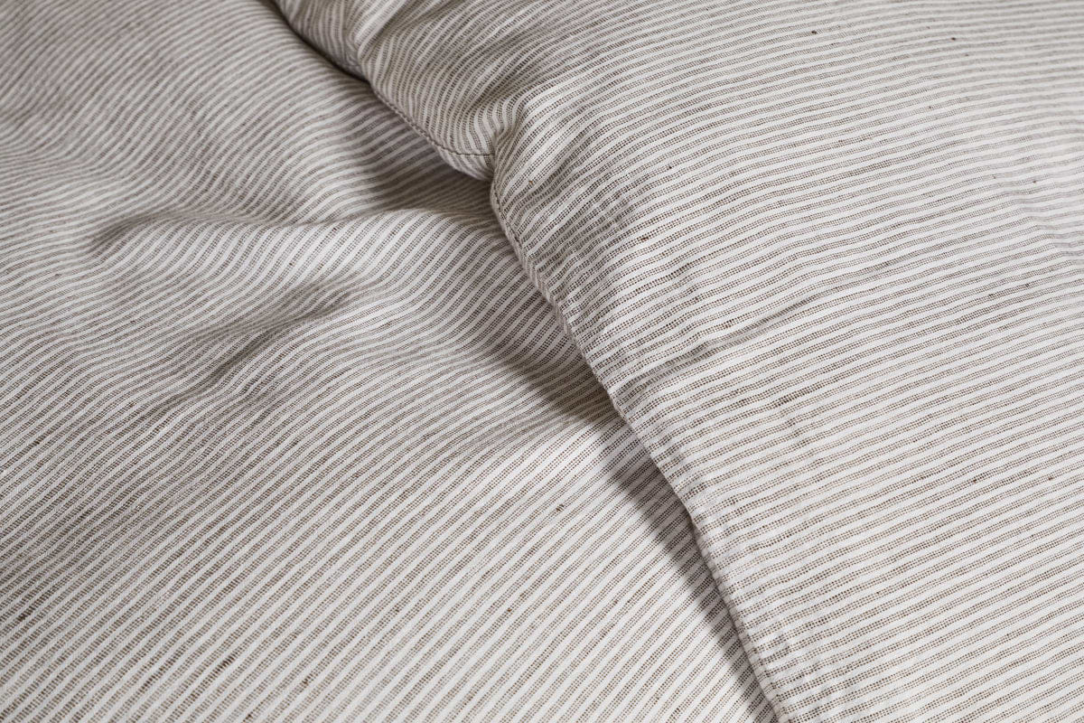 Close-up of the nkuku Borba Hemp & Cotton Duvet Cover in Espresso, featuring breathable, soft fabric with fine beige and white horizontal stripes and a slightly rumpled, textured look.