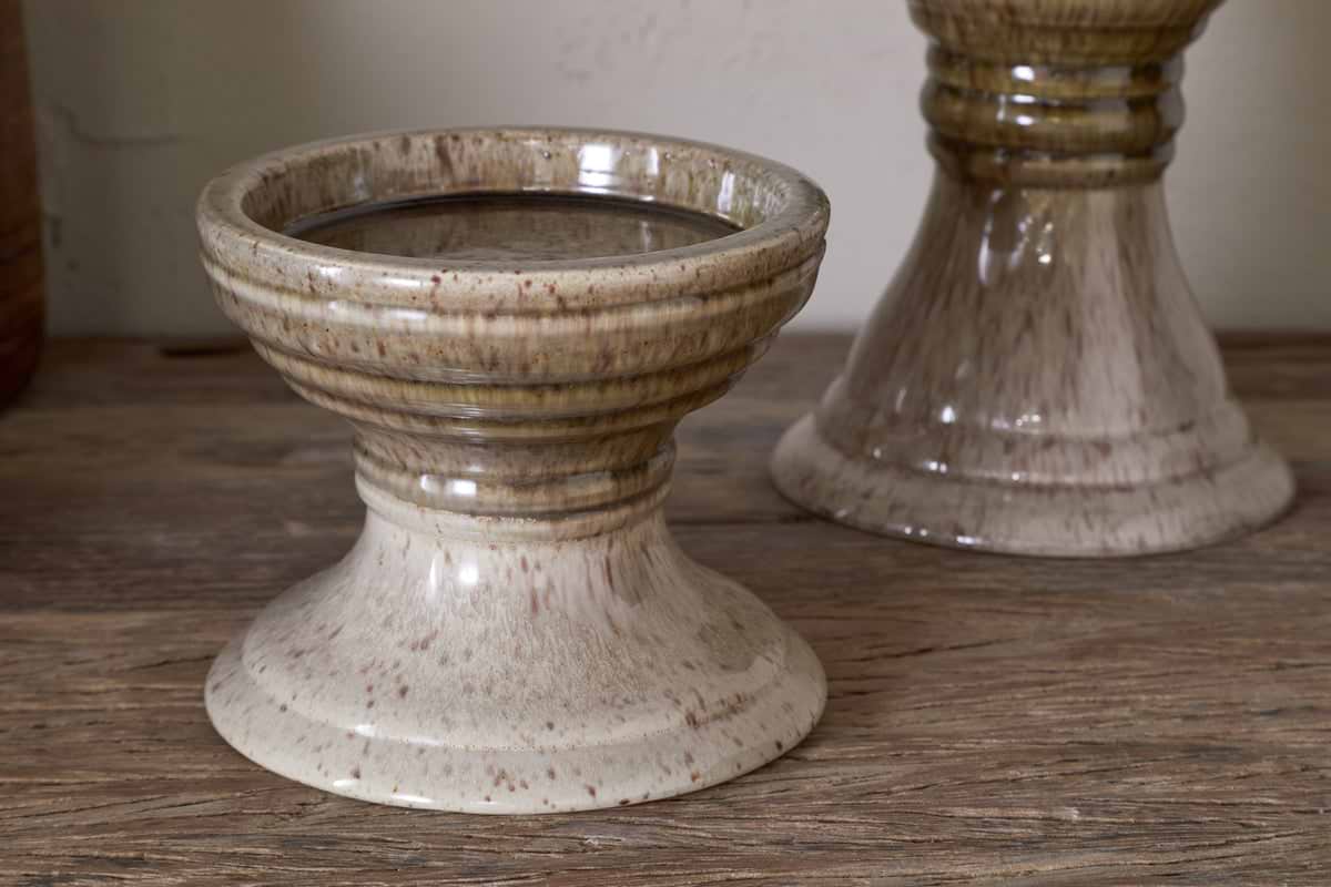 The Cabra Reactive Glaze Candle Holder by nkuku in Olive & Natural adds a unique touch to rustic decor with its distinctive design.