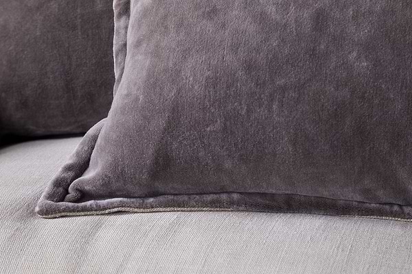 Close-up of two nkuku Dhara Velvet Cushion Covers in charcoal, resting on a light-colored fabric surface. The visible velvet texture gives each cover a plush, cozy, and decorative look.