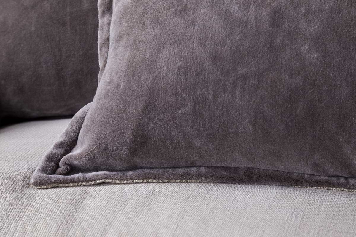 Close-up of two nkuku Dhara Velvet Cushion Covers in charcoal, resting on a light-colored fabric surface. The visible velvet texture gives each cover a plush, cozy, and decorative look.