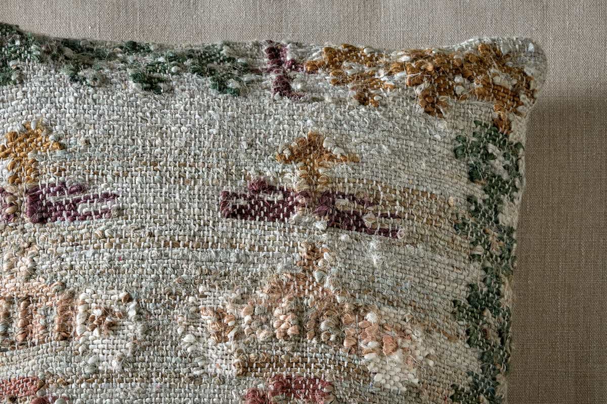 Close-up of the Dantri Jute & Cotton Cushion Cover by nkuku, featuring a tapestry-like design in soft grey with intricate geometric and floral patterns that add unique charm to its rustic, textured background.