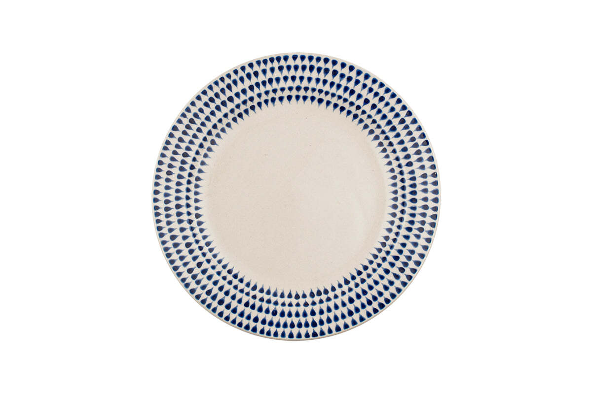 The Indigo Drop Dinnerware Set – Cream & Indigo (Set of 12) by nkuku features handmade ceramic plates from Vietnam with a cream center and a hand-painted indigo teardrop border on a white background.
