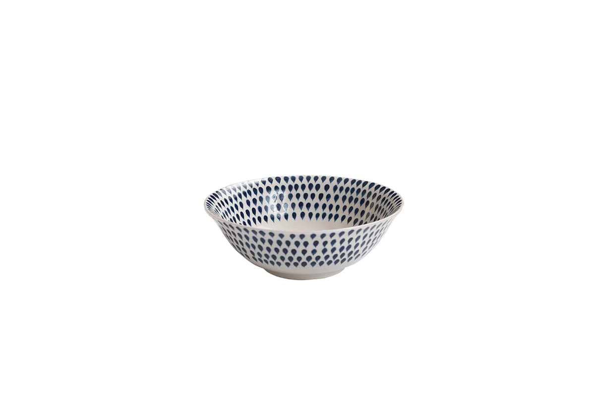 The Indigo Drop Dinnerware Set - Cream & Indigo by nkuku includes 12 handmade ceramic pieces from Vietnam, each featuring hand-painted blue dots on gently sloping sides, inspired by traditional Indigo Drop designs.