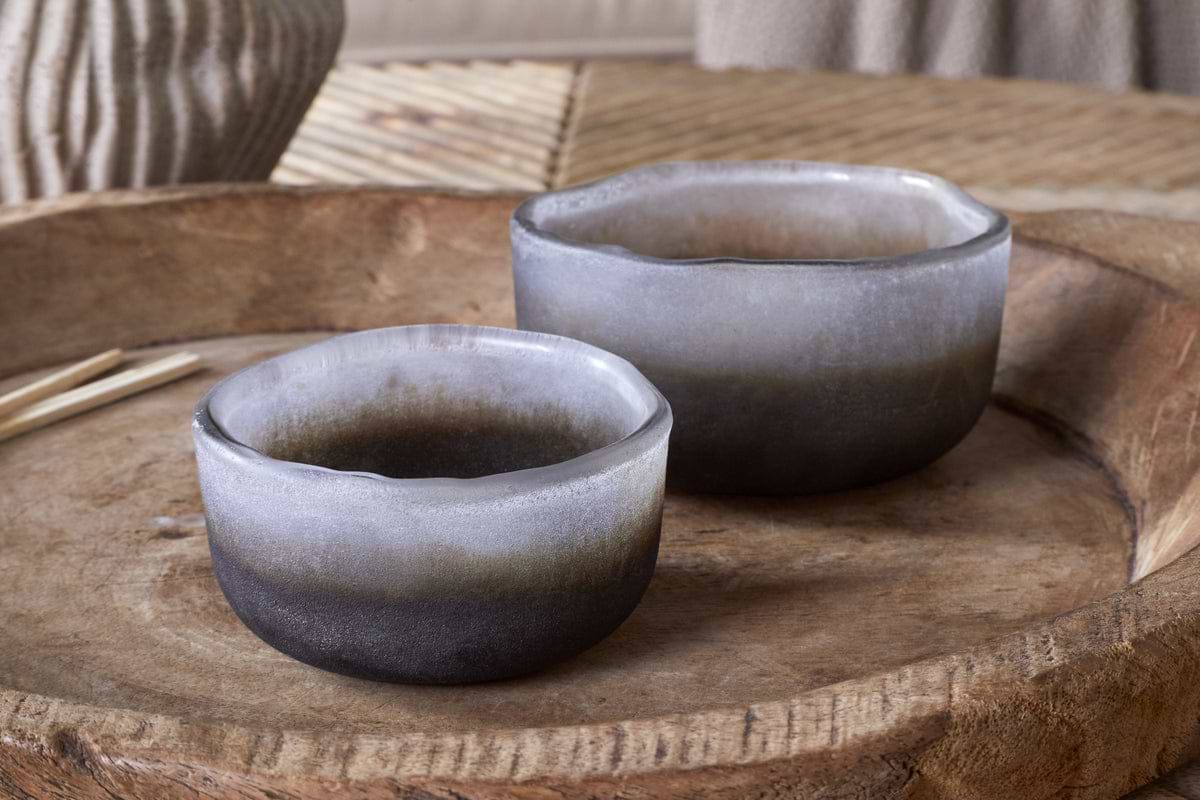 The nkuku Janka Tealight Holders - Smoked Charcoal (Set of 2) feature round, frosted glass bowls with a dark-to-light gray gradient and rustic, uneven rims, adding charm to any home décor on their wooden tray.