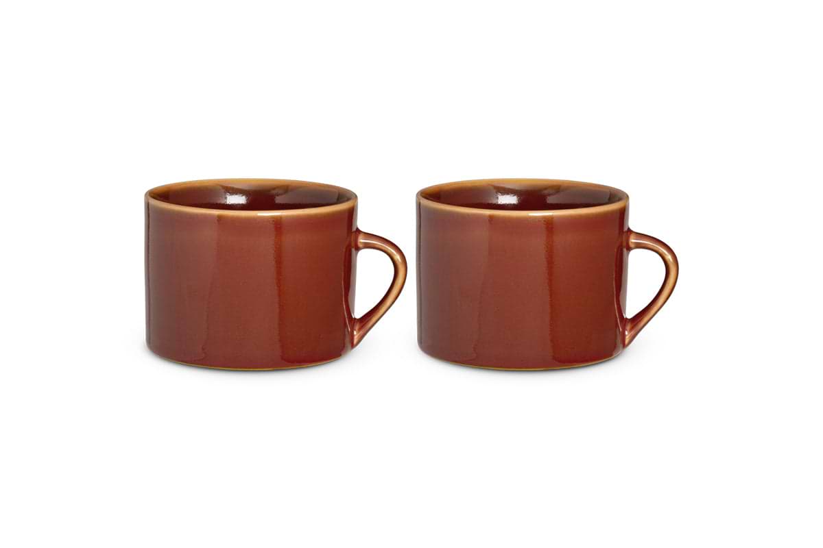 Two large nkuku Kalini Mugs in glossy amber, kiln-fired for durability, sit side by side against a white background. Each mug has a round handle, slightly rounded lip, and smooth straight-sided shape. Sold as a set of 2.