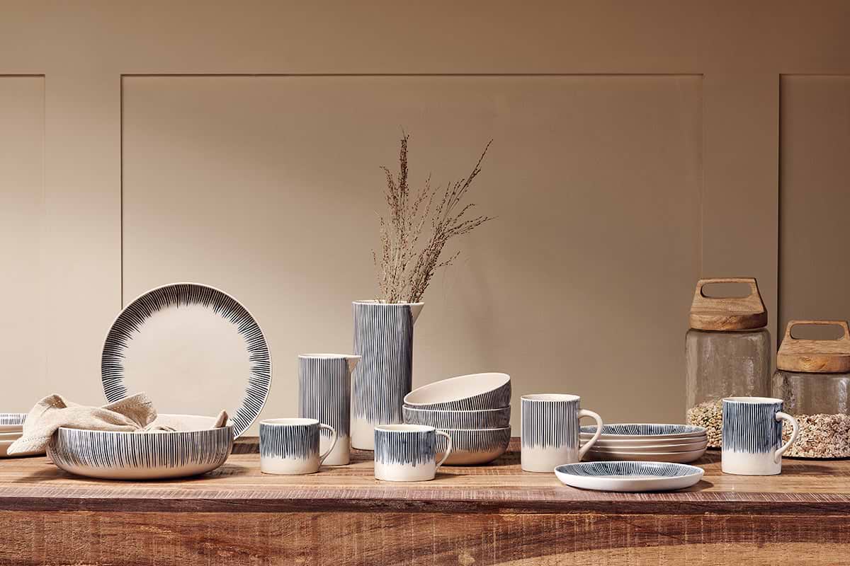 The nkuku Karuma Ceramic Mug - Small (Set of 2) features a minimalist blue stripe design, inspired by Vietnamese ceramics. These handmade mugs are part of a collection that celebrates simple elegance.