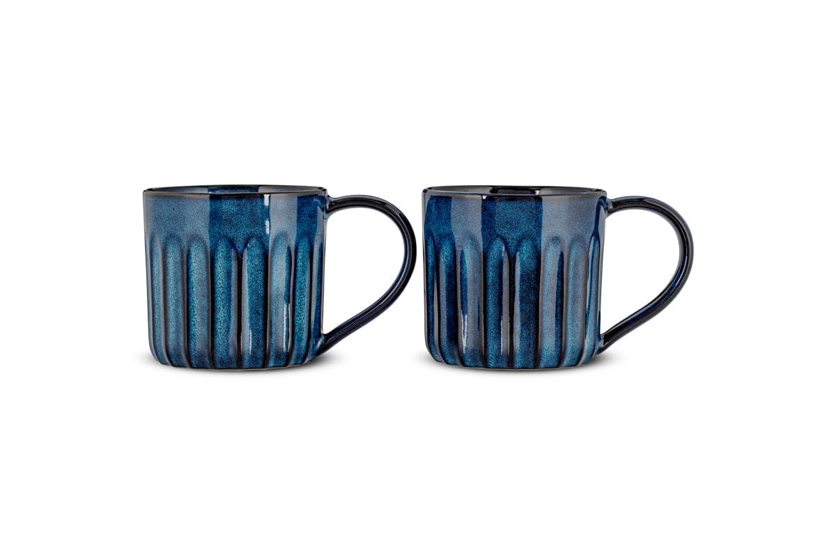 The nkuku Moda Mug - Deep Blue (Set of 2) features grooved ceramic mugs with vertical ridges, a deep blue glaze, black accents on the rims and handles, slightly glossy finishes, and rounded handles, shown side by side on a white background.