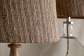 Close-up of the nkuku Nadee Banana Leaf Lampshade in natural, woven with warm brown tones, with another similar lampshade softly blurred in the background.