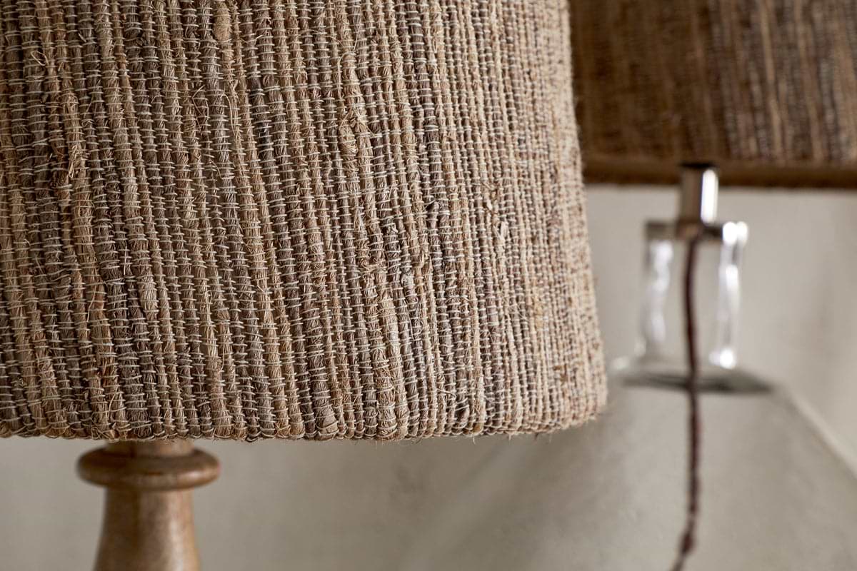 Close-up of the nkuku Nadee Banana Leaf Lampshade in natural, woven with warm brown tones, with another similar lampshade softly blurred in the background.