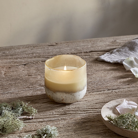 Candle on a wooden surface with natural elements and a box in the background