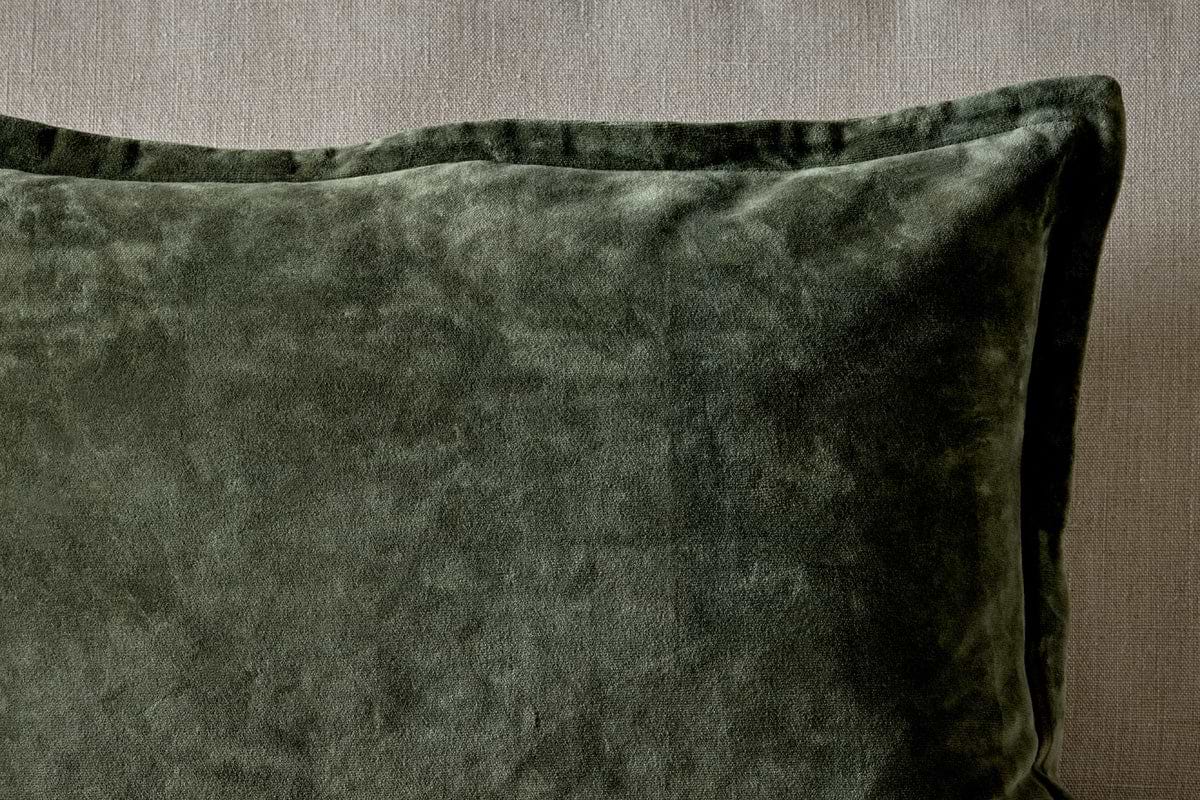 A close-up of the nkuku Pilani Velvet & Linen Cushion Cover in Moss, highlighting its deep green velvet against a textured linen backdrop.