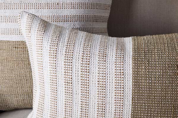 Two nkuku Samata Recycled Cushion Covers in moss, featuring textured horizontal stripes and a simple, modern design, are displayed against a beige background. Each cushion cover blends wide and narrow stripes for visual interest.