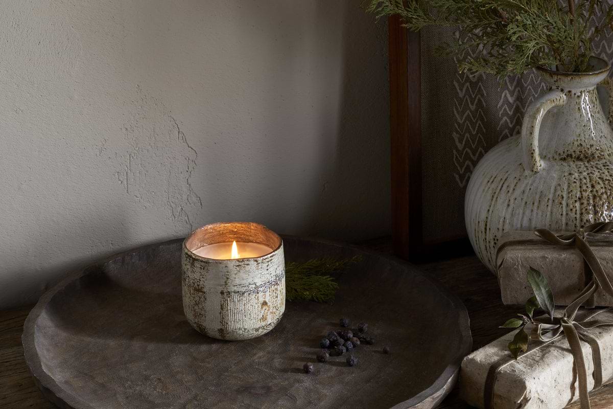 The nkuku Juniper & Fir 1 Wick Scented Candle comes in a reusable vessel, ideal for adding a unique fragrance to any space.