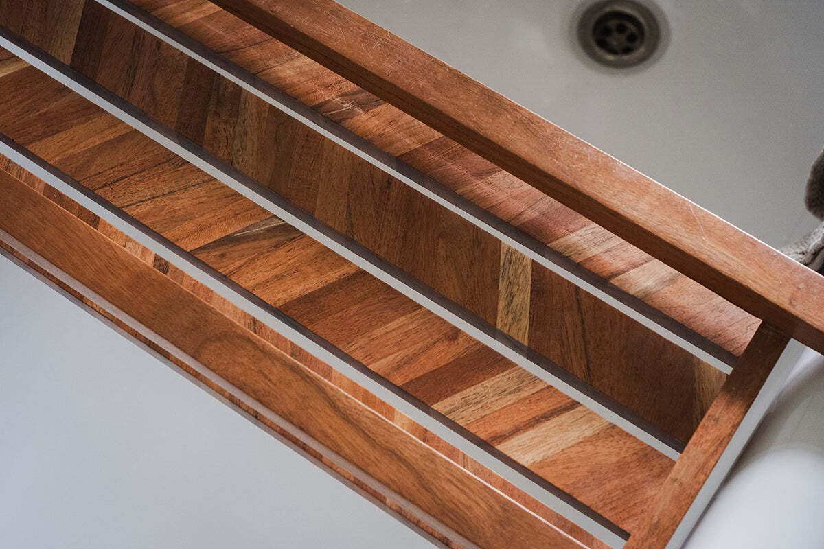 Close-up of the nkuku Sukha Mango Bath Bridge - Natural, showcasing its diagonal grain patterns and warm mango wood tones, adding geometric elegance and a spa-like feel to the bathroom with soft shadows against a white background.